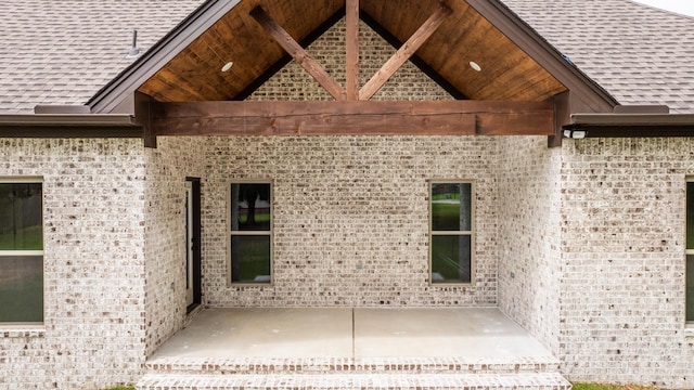 exterior space featuring brick siding and a shingled roof
