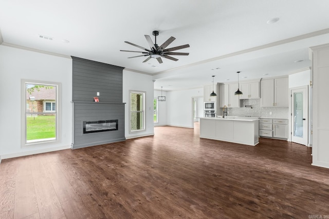 unfurnished living room with ceiling fan, a fireplace, dark wood-style floors, visible vents, and crown molding