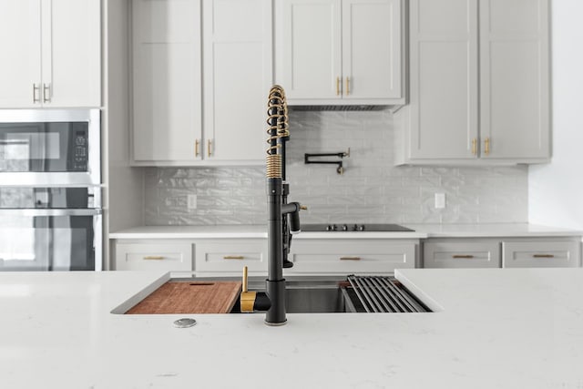 kitchen with light stone counters, tasteful backsplash, white cabinetry, and stainless steel appliances