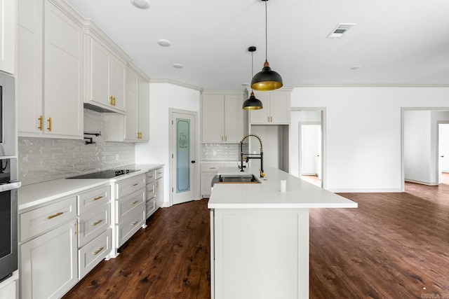 kitchen featuring tasteful backsplash, black electric stovetop, light countertops, dark wood-style flooring, and a sink