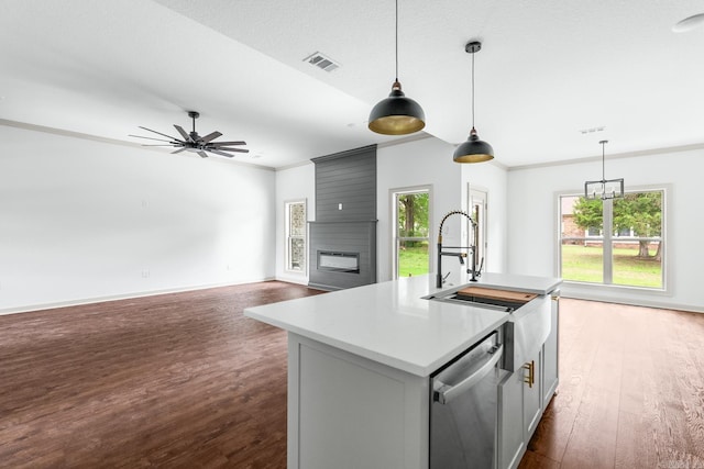 kitchen with hanging light fixtures, dishwasher, a fireplace, dark wood-style floors, and visible vents