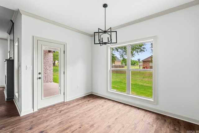 unfurnished dining area with crown molding, an inviting chandelier, wood finished floors, and plenty of natural light