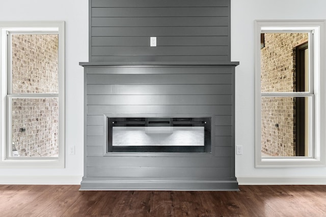 interior details with baseboards, wood finished floors, and a glass covered fireplace