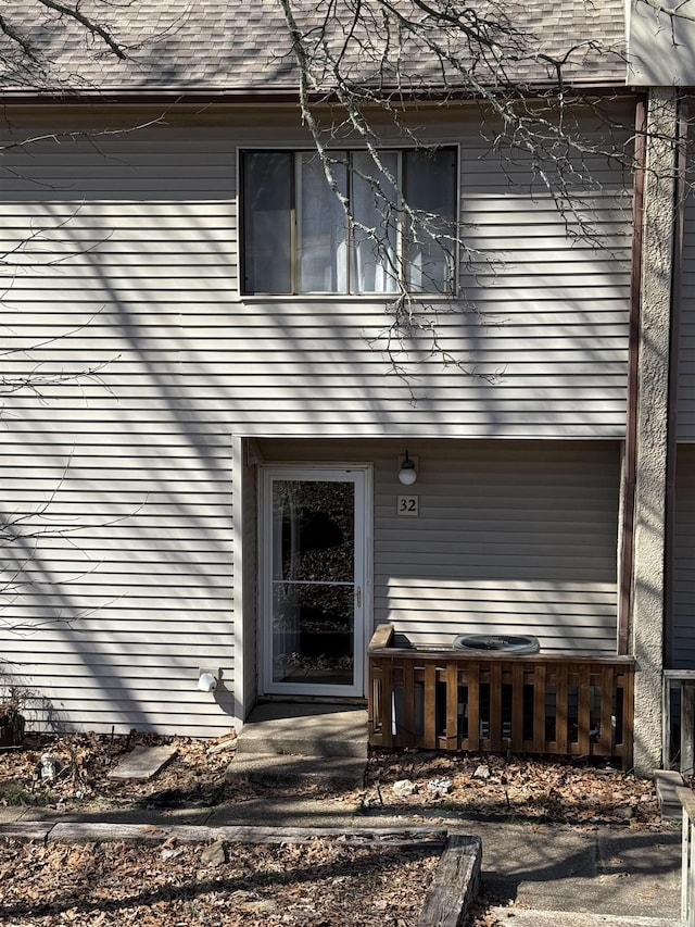 doorway to property with roof with shingles