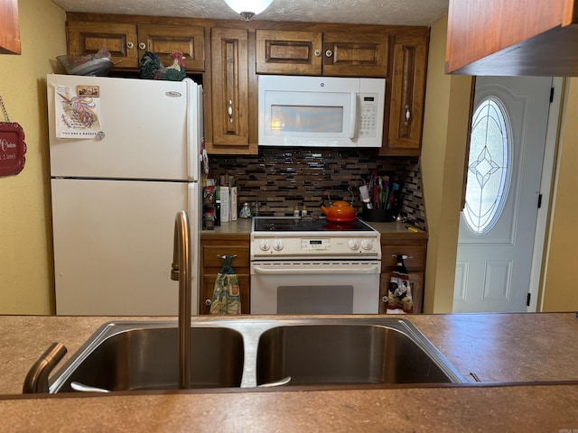 kitchen featuring white appliances, brown cabinetry, a sink, and decorative backsplash