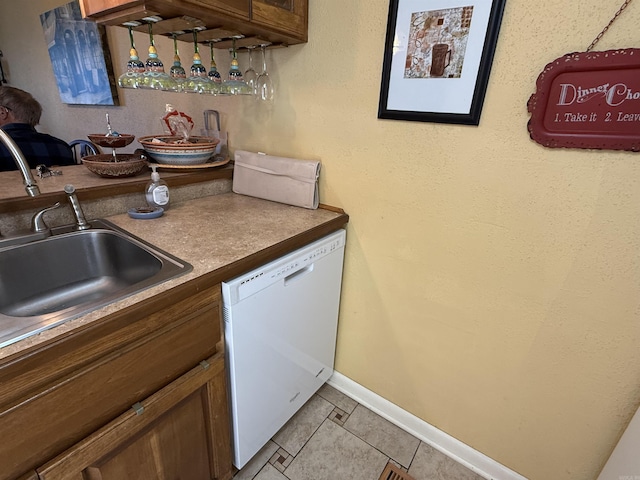 kitchen featuring a sink, baseboards, dishwasher, and light tile patterned flooring