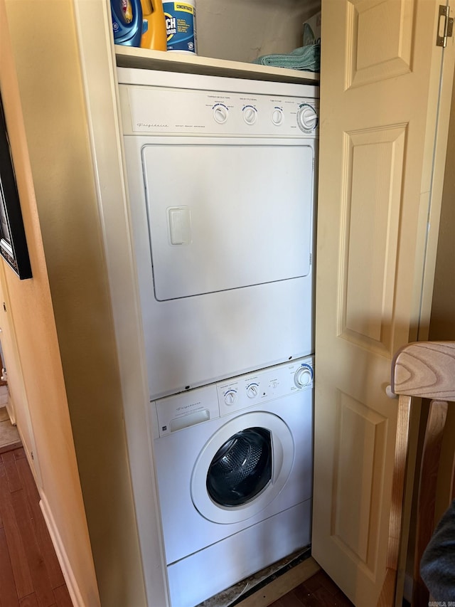 clothes washing area featuring laundry area, dark wood-style flooring, and stacked washer / drying machine