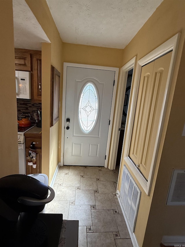 foyer featuring a textured ceiling, visible vents, and baseboards