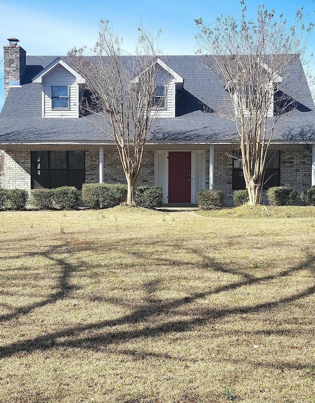 view of front of property featuring a shingled roof, brick siding, and a front lawn