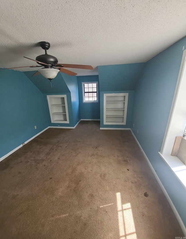 additional living space featuring built in shelves, carpet floors, and a textured ceiling