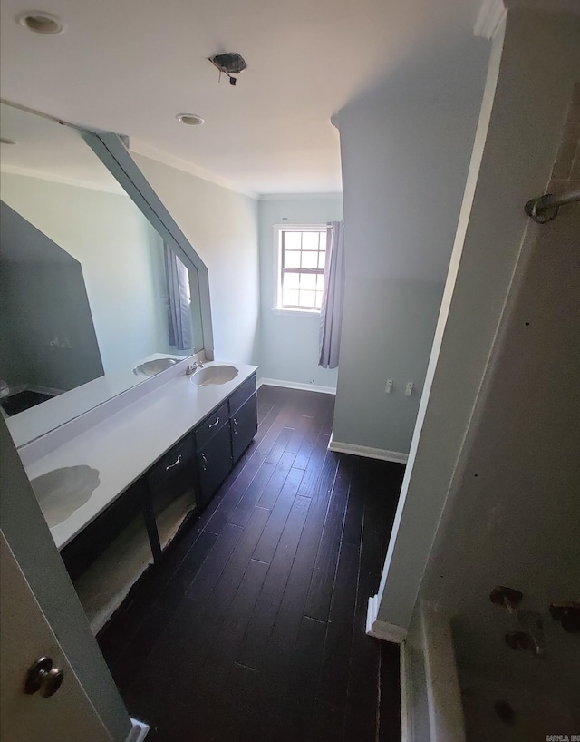 bathroom featuring double vanity, a sink, baseboards, and wood finished floors