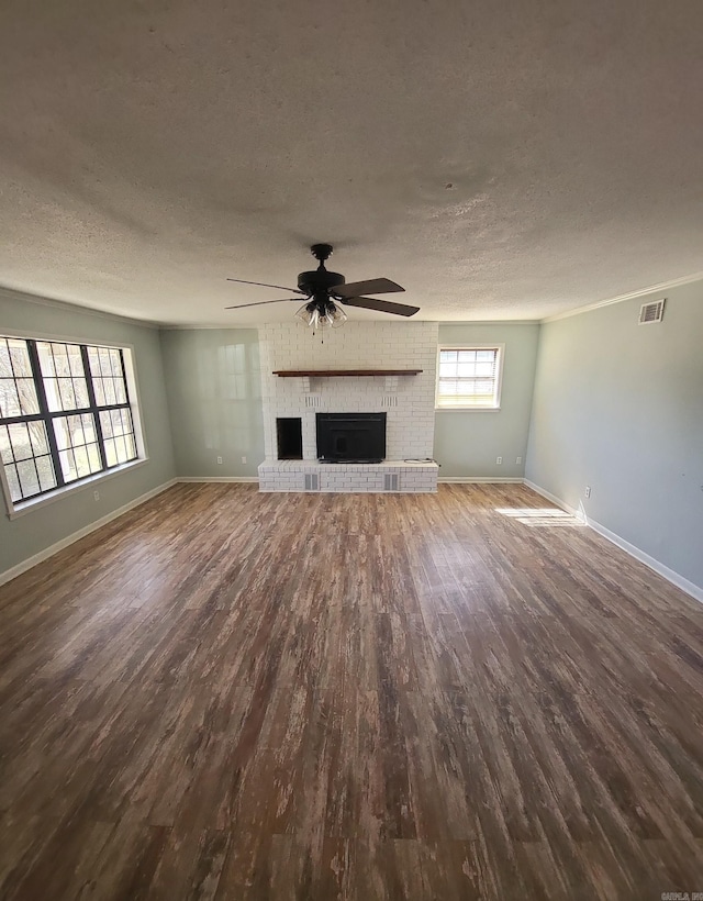 unfurnished living room featuring a textured ceiling, a fireplace, wood finished floors, visible vents, and baseboards