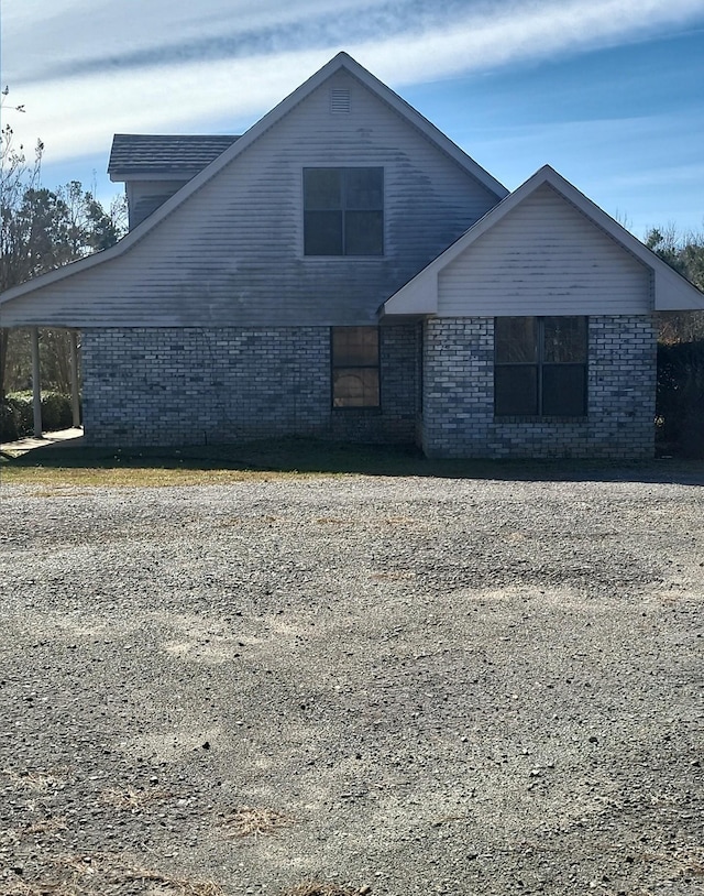 view of side of home featuring driveway and brick siding