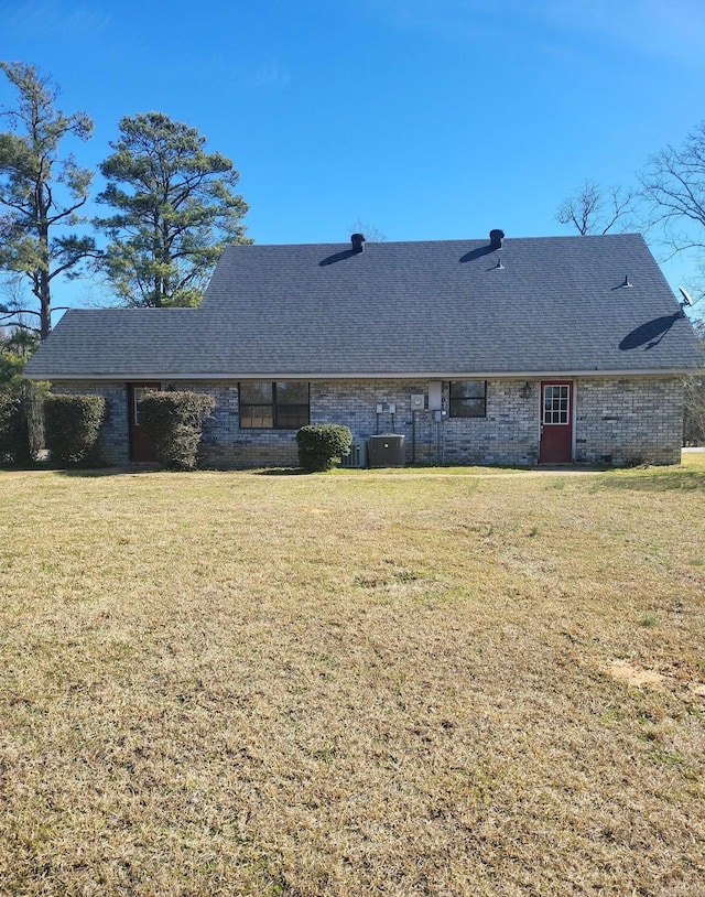 rear view of property with roof with shingles, a yard, and brick siding