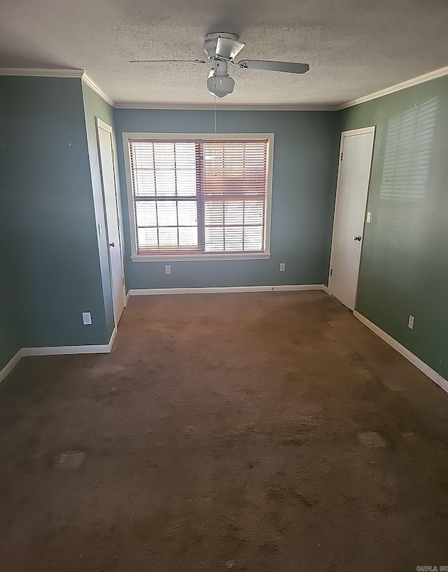 spare room featuring a textured ceiling, ornamental molding, dark carpet, and baseboards