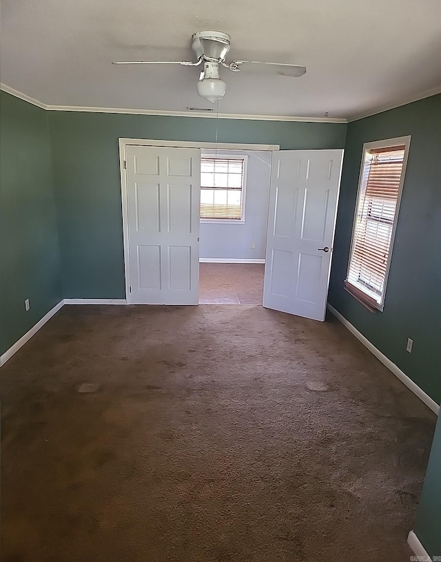 unfurnished bedroom with ceiling fan, carpet floors, ornamental molding, and baseboards