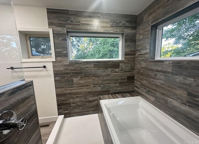 full bath featuring a tub to relax in, walk in shower, and visible vents