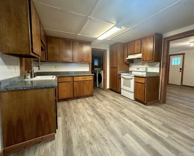 kitchen with white range with electric cooktop, dark countertops, washer and dryer, under cabinet range hood, and a sink