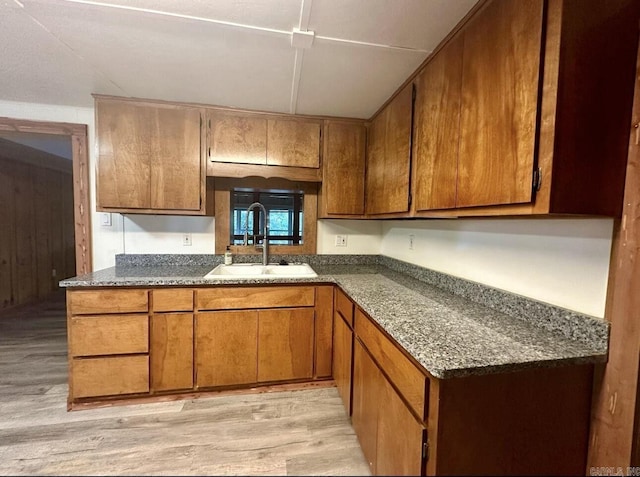 kitchen featuring brown cabinetry, light wood-style floors, and a sink