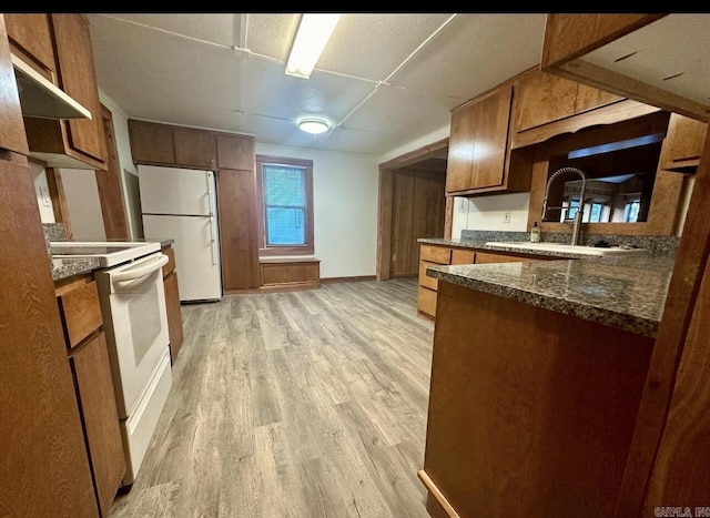 kitchen with white appliances, a sink, baseboards, light wood-type flooring, and brown cabinets