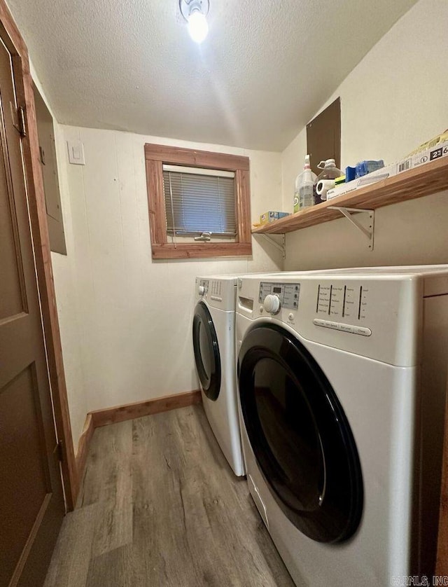 laundry area with a textured ceiling, laundry area, washing machine and dryer, and wood finished floors