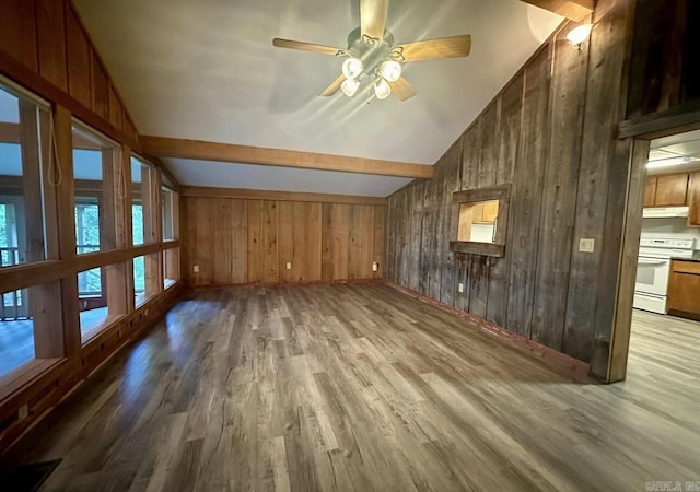 unfurnished living room with vaulted ceiling with beams, wooden walls, a ceiling fan, and wood finished floors