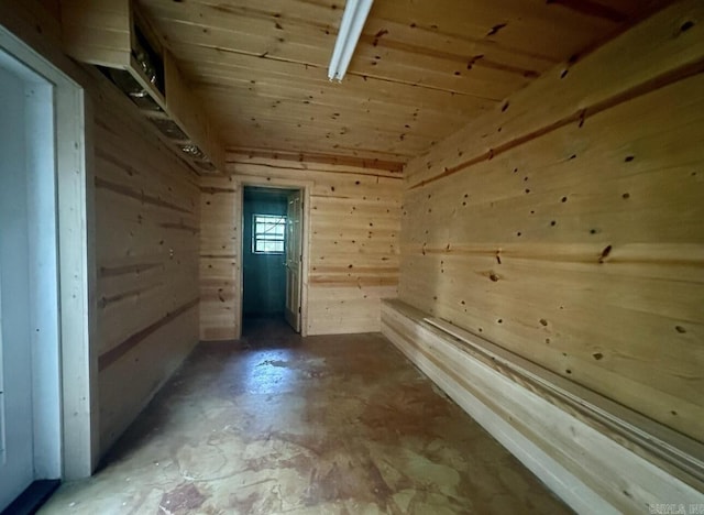 bonus room with concrete floors and wooden walls