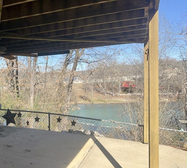 view of patio with a water view and fence