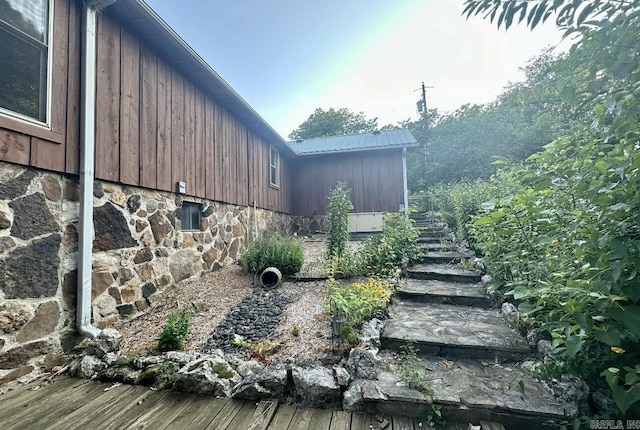 view of side of home featuring metal roof and stairway