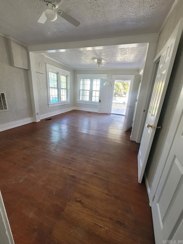 unfurnished living room featuring ceiling fan, a textured wall, dark wood-style flooring, and baseboards