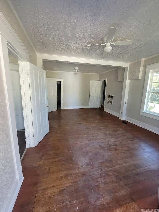 empty room with dark wood-style floors, visible vents, baseboards, and a ceiling fan