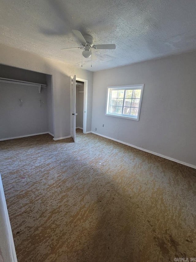 unfurnished bedroom featuring ceiling fan, a textured ceiling, baseboards, and carpet flooring