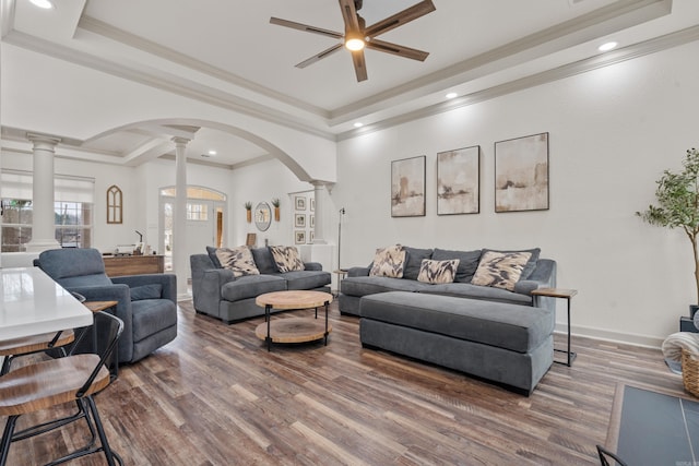 living room with arched walkways, baseboards, a raised ceiling, and ornate columns