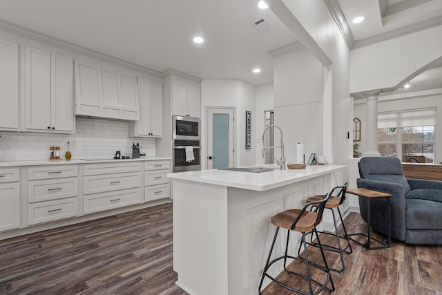 kitchen featuring a breakfast bar, dark wood-style flooring, visible vents, and stainless steel microwave