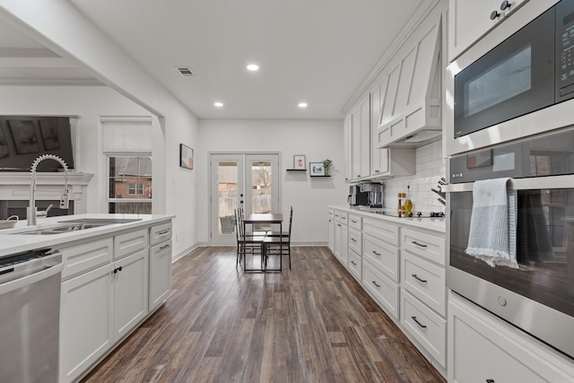 kitchen featuring dark wood finished floors, light countertops, backsplash, appliances with stainless steel finishes, and a sink