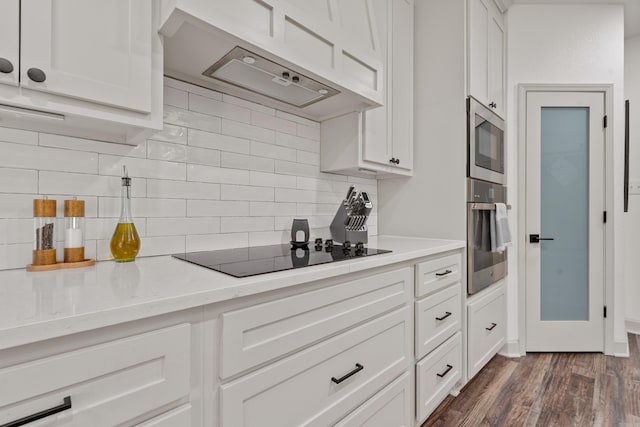 kitchen with white cabinets, under cabinet range hood, stainless steel appliances, and dark wood finished floors