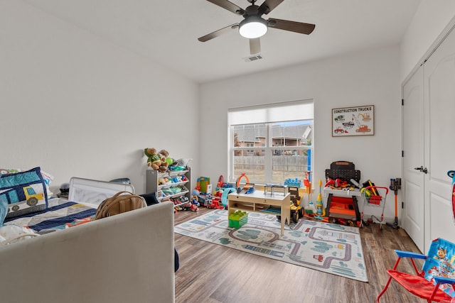 recreation room with a ceiling fan, visible vents, and wood finished floors