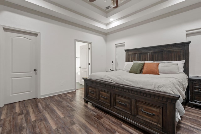 bedroom featuring baseboards, visible vents, a raised ceiling, ensuite bath, and dark wood-style flooring