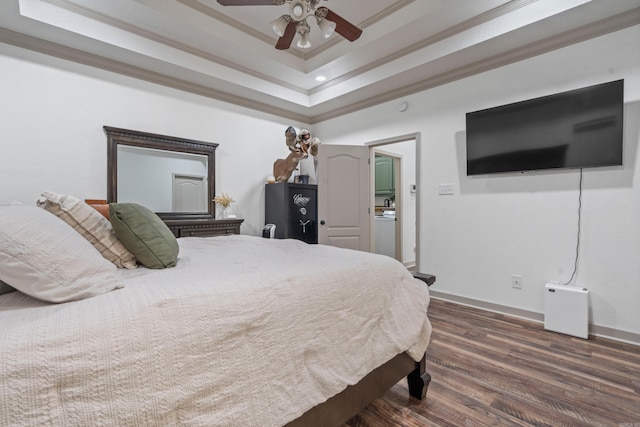 bedroom featuring baseboards, dark wood finished floors, a ceiling fan, ornamental molding, and a tray ceiling