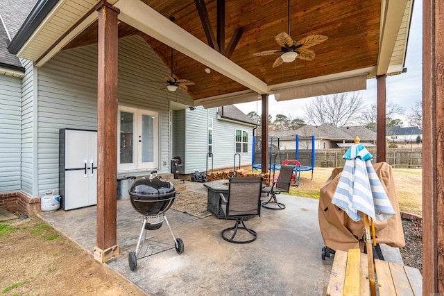 view of patio featuring ceiling fan, a trampoline, fence, and french doors