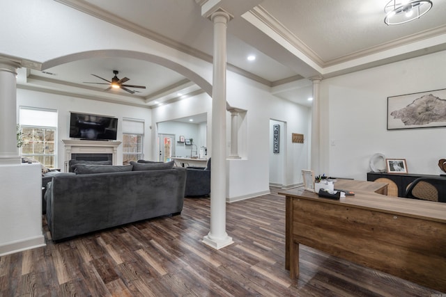 living area with a tray ceiling and decorative columns