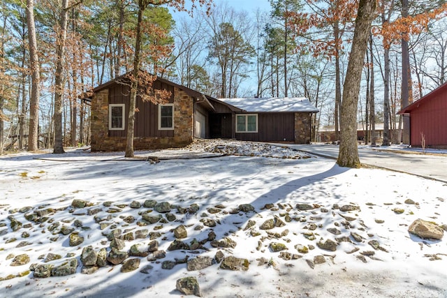 view of front facade featuring an attached garage, stone siding, and board and batten siding