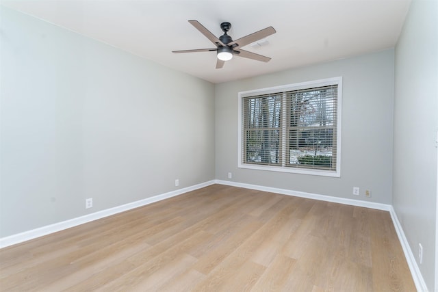 empty room featuring a ceiling fan, visible vents, light wood finished floors, and baseboards