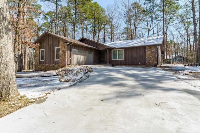 view of front of property featuring board and batten siding, concrete driveway, stone siding, and a garage