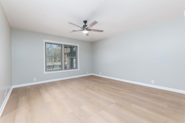 spare room with ceiling fan, light wood-type flooring, and baseboards