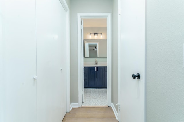 corridor featuring light wood finished floors and a sink