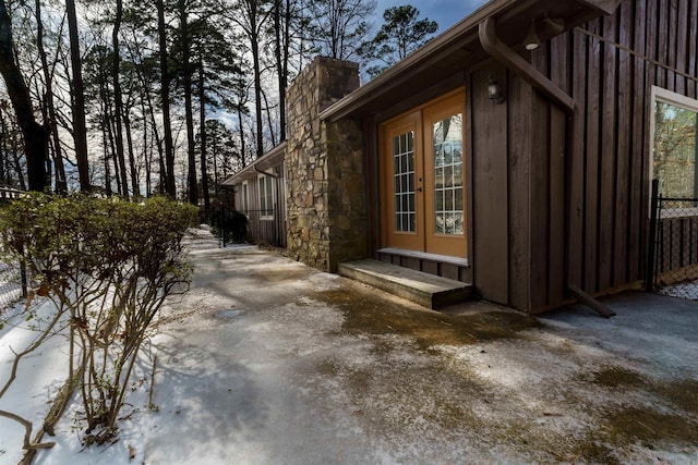 view of property exterior with entry steps, stone siding, french doors, and a chimney