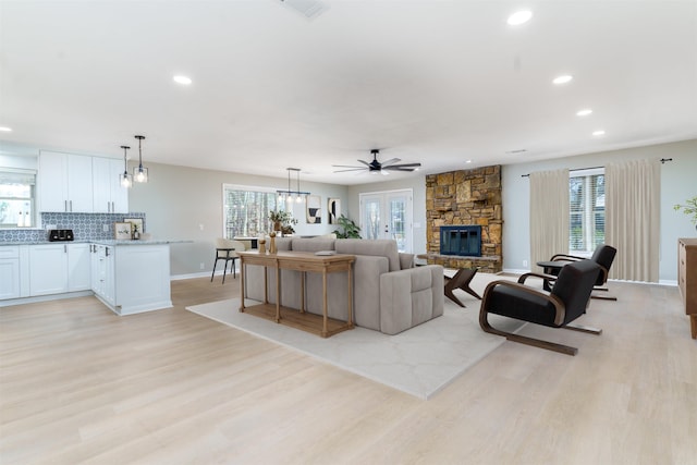 living area featuring plenty of natural light, visible vents, a fireplace, and light wood-style flooring