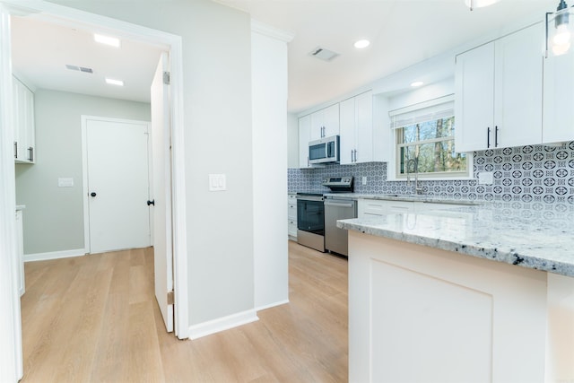 kitchen with light stone counters, appliances with stainless steel finishes, visible vents, and decorative backsplash