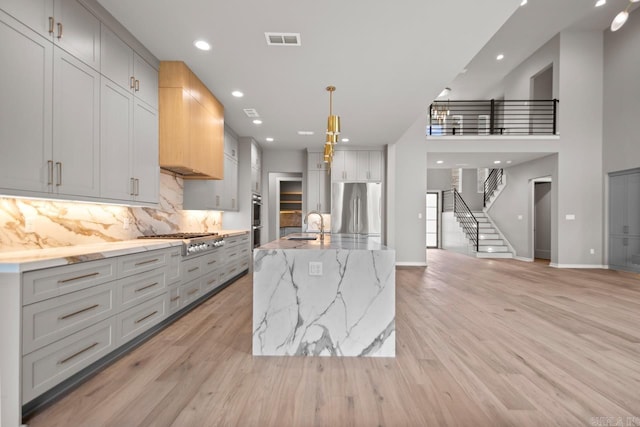 kitchen with appliances with stainless steel finishes, light wood-style flooring, visible vents, and decorative backsplash